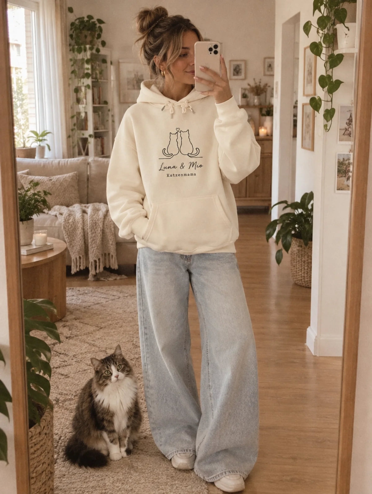 Frau trägt den Katzenmama Lineart-Hoodie von Mr. Fluffel vor dem Spiegel